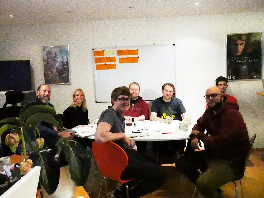 Das memedia-Team beim Core-Value-Coaching am Besprechungstisch, im Hintergrund ein Whiteboard mit Notizen